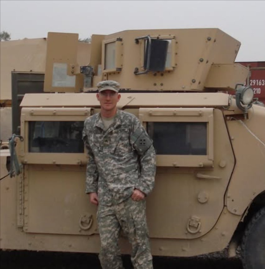 Christopher Chaos in Army uniform beside a military vehicle